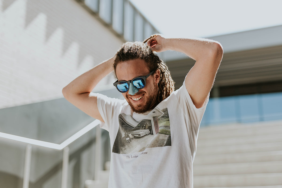 Man on his way out while fixing his long hair wearing awesome blue sunglasses and his awesome blue Nöz stick nose sunscreen. 