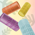 Load image into Gallery viewer, Nöz sunscreen sticks are in four colors, orange, yellow, purple, and blue with a colorful leaf design in the background. 
